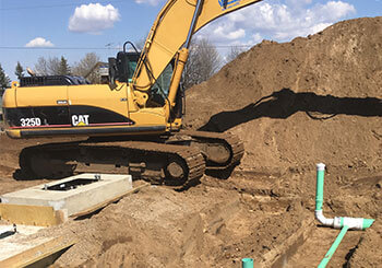 Excavator placing septic pipe